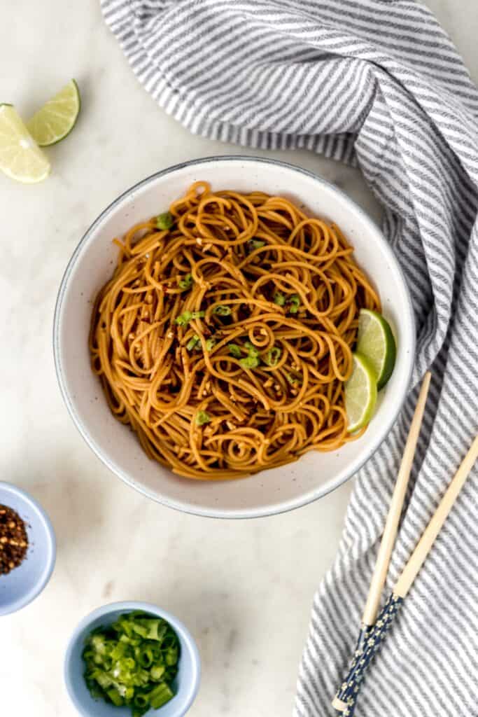 overhead view easy sesame noodles in white bowl with napkin and chop sticks