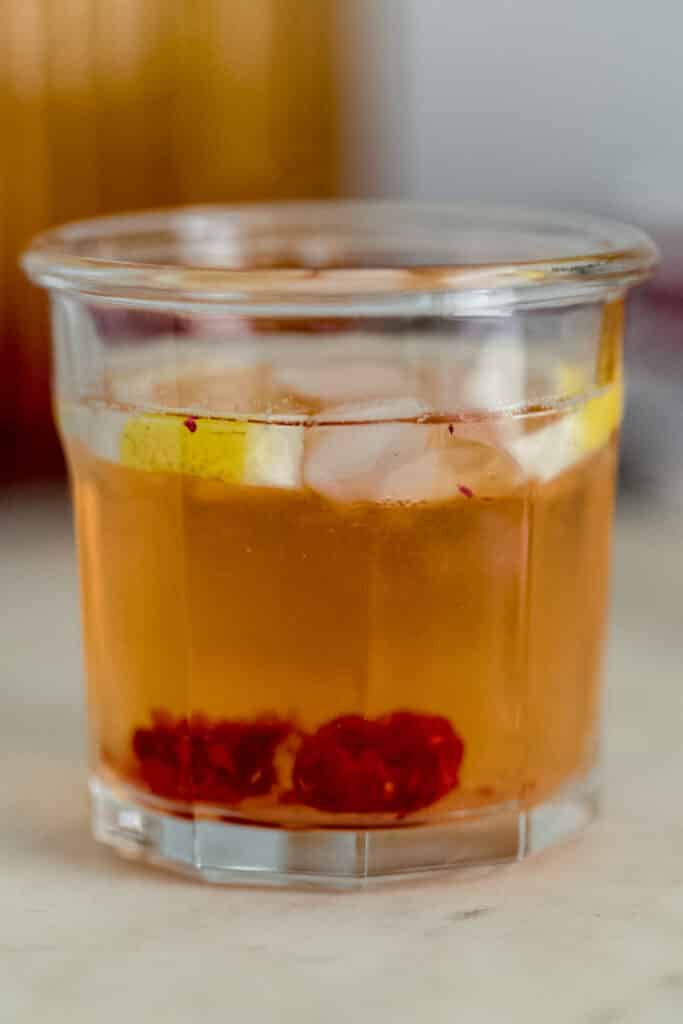 side view glass iced green tea with lemon and raspberries