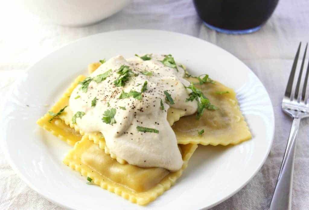 Finished sauce on ravioli on white plate. 