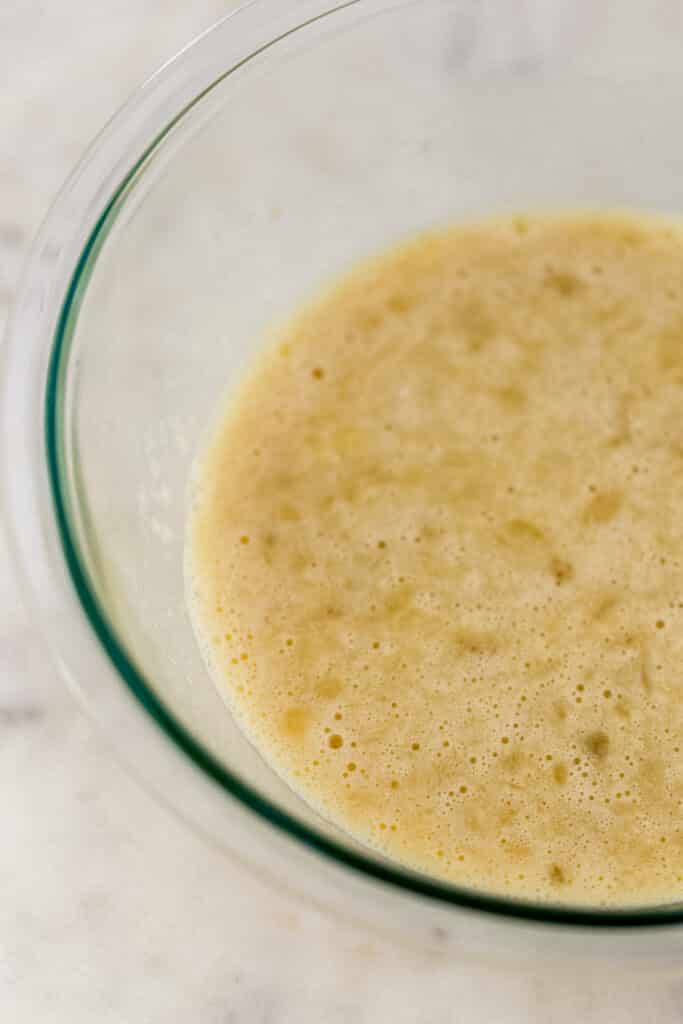 mashed banana, eggs, maple syrup, and vanilla in glass mixing bowl 