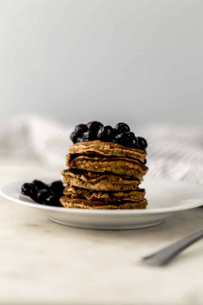 banana pancakes topped with sauteed blueberries on white plate 