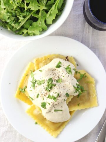 overhead ravioli topped with sauce on white plate