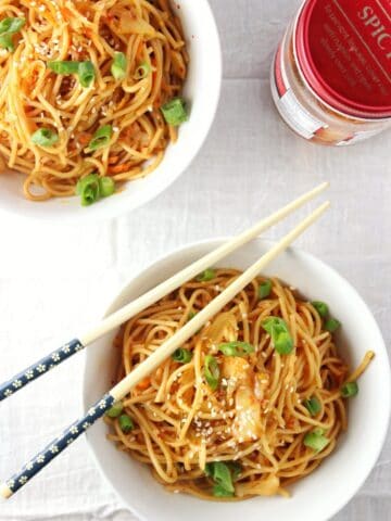 overhead view of kimchi sesame noodles in two bowls with chopsticks