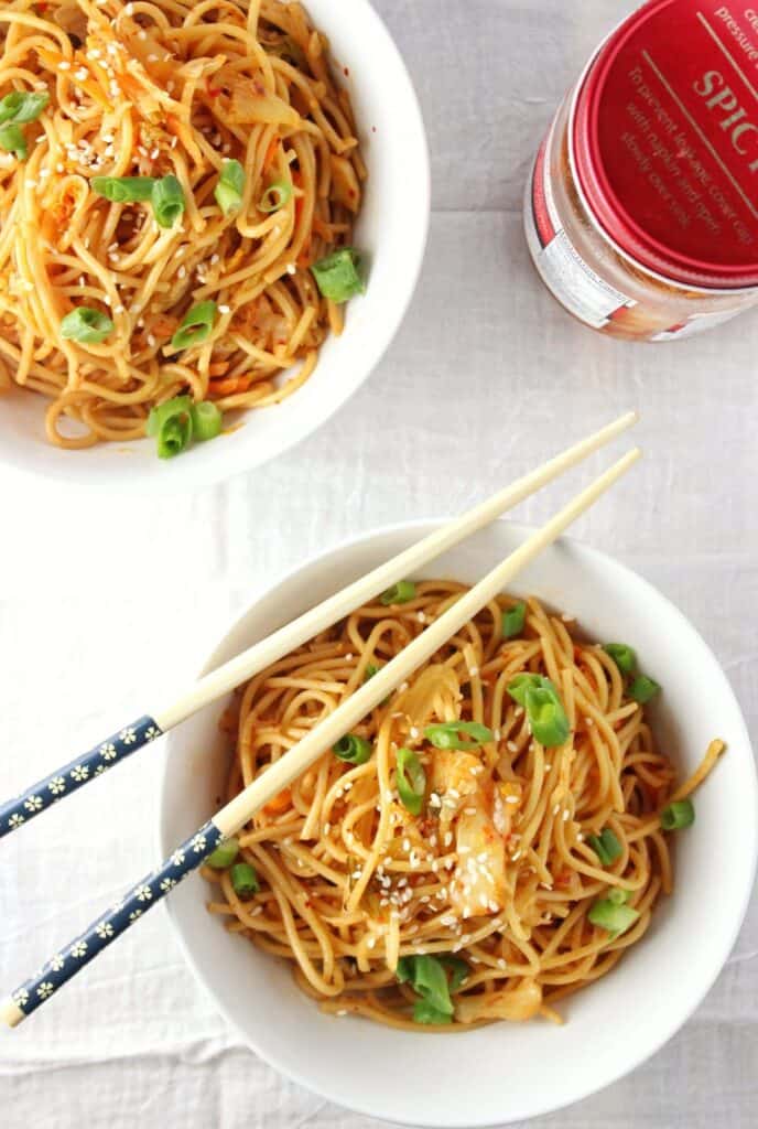 overhead view of kimchi sesame noodles in two bowls with chopsticks