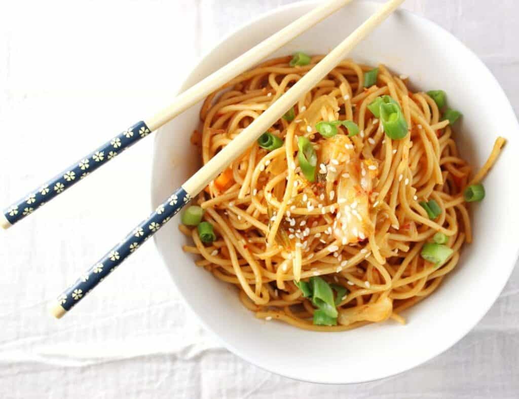 single bowl of spicy kimchi sesame noodles with chop sticks 