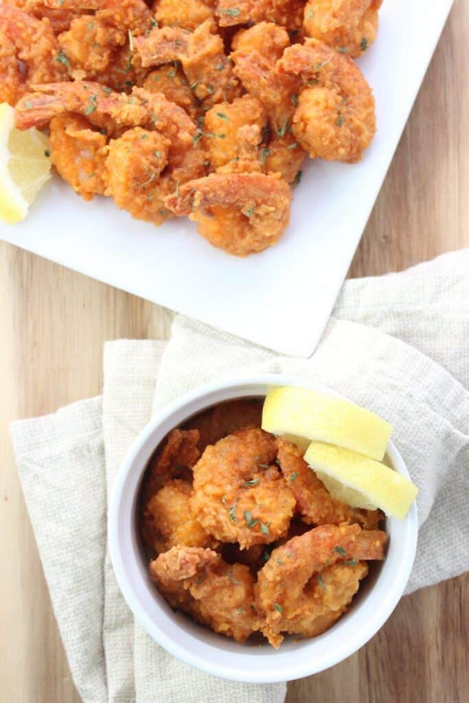 overhead view of Buffalo Shrimp on plate and in bowl with lemon wedges 