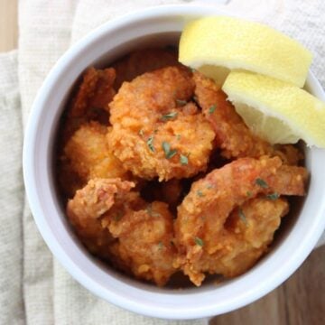 overhead view of Buffalo Shrimp in a bowl with lemon wedges