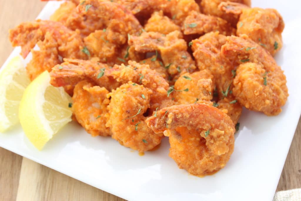 Close-up side view of Easy Buffalo Shrimp Recipe on white plate with lemons