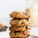 close up side view white plate with a stack of five oatmeal raisin cookies on it.