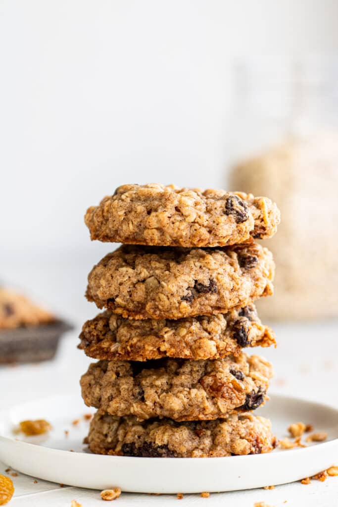 close up side view white plate with a stack of five oatmeal raisin cookies on it.