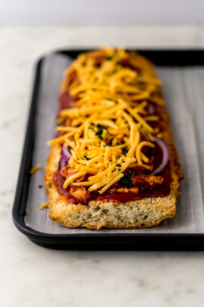 parchment lined baking sheet with barbecue French bread pizza on it before baking. 