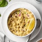 overhead view chickpea salad in white bowl with lemon wedge on white plate with spoon