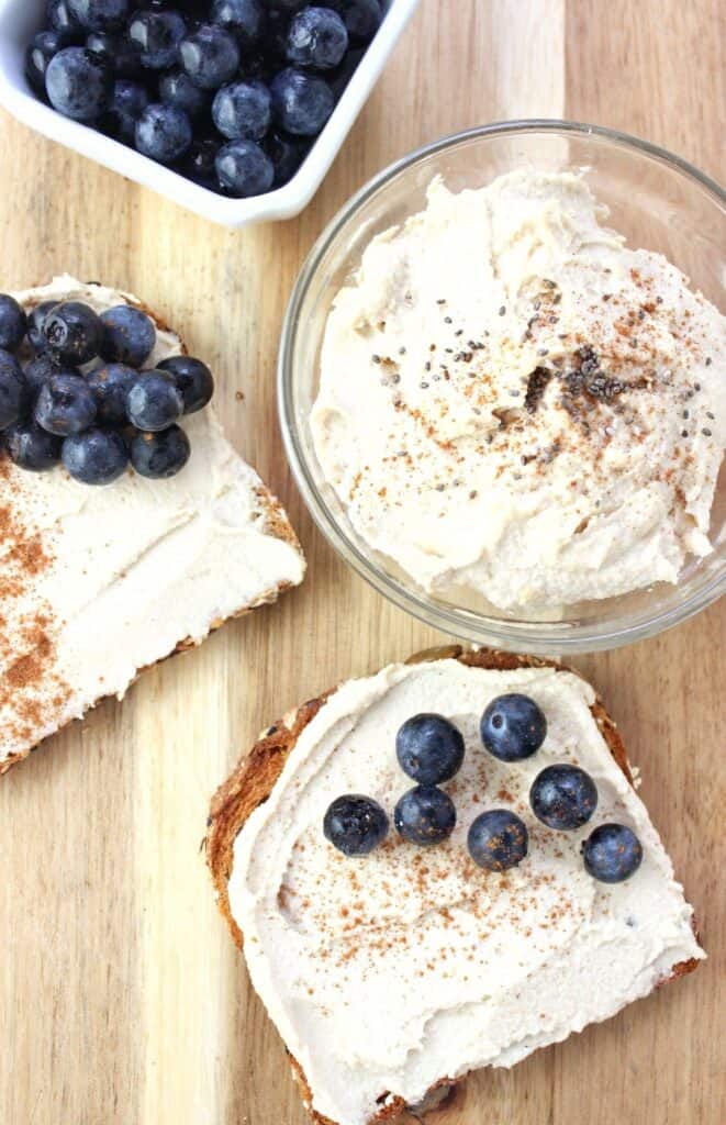 overhead view of glass of cashew butter with two pieces of toast topped with butter and fresh blueberries 