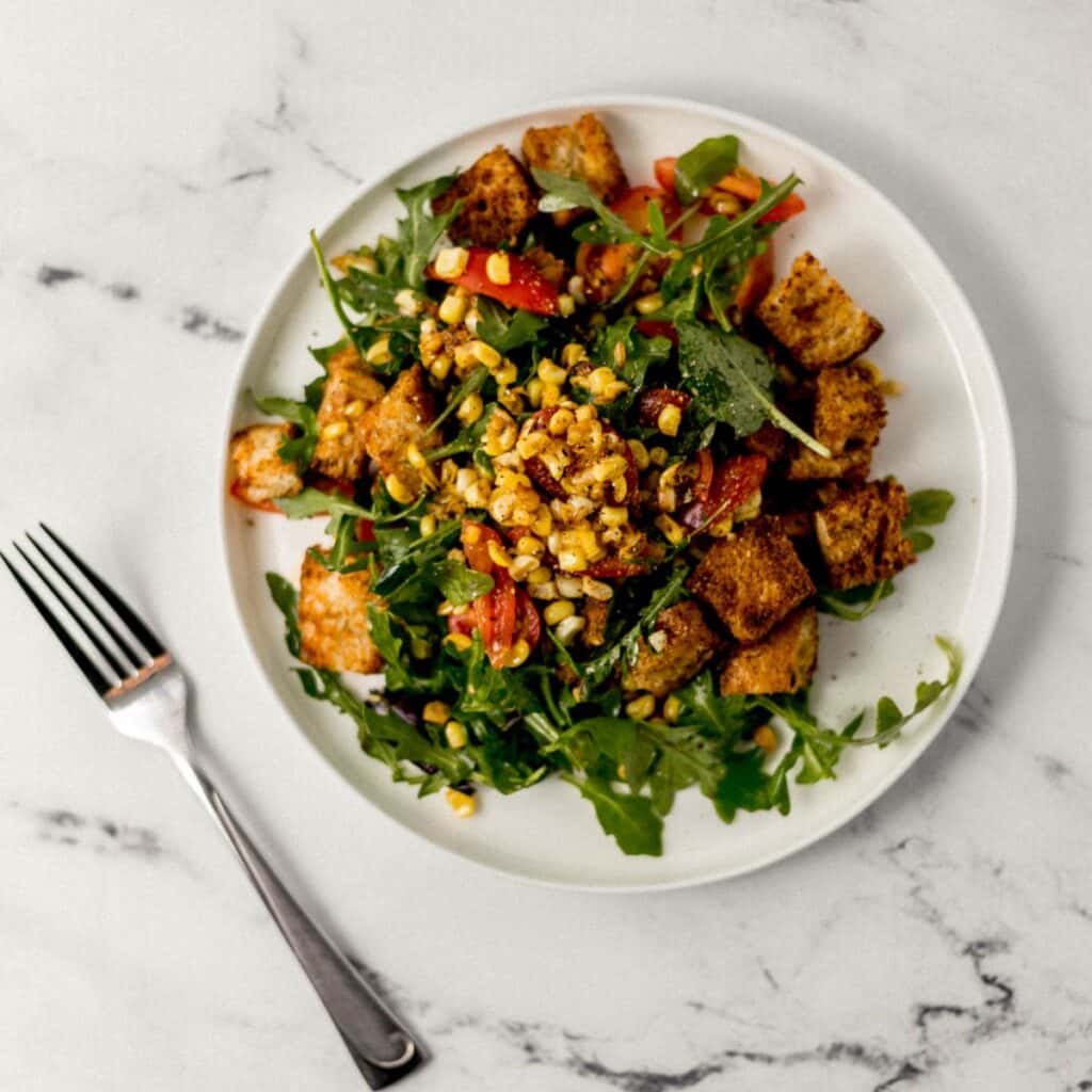 overhead view of salad on white plate beside fork