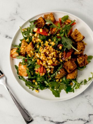 overhead view of salad on white plate beside fork