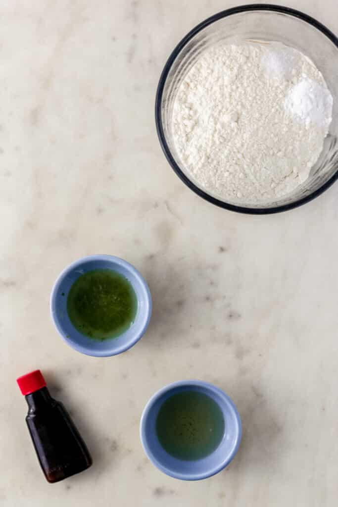 ingredients to make margarita cupcakes in small bowls on marble surface 