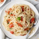 overhead view of pasta and tomato on white plate with fork.