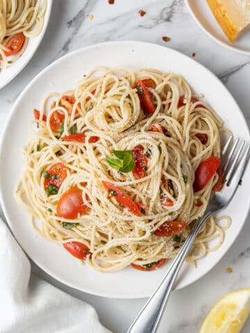overhead view of pasta and tomato on white plate with fork.