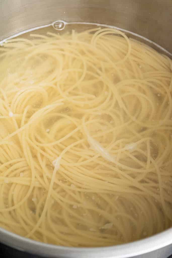 spaghetti pasta being cooked in a pot with water