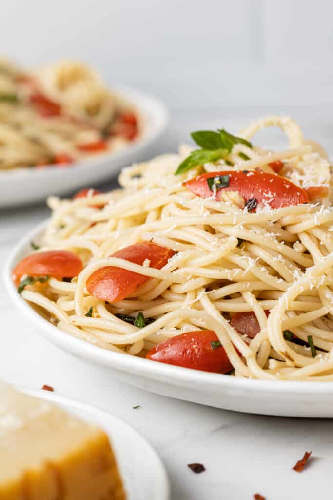 close up side view tomato basil pasta on white plate