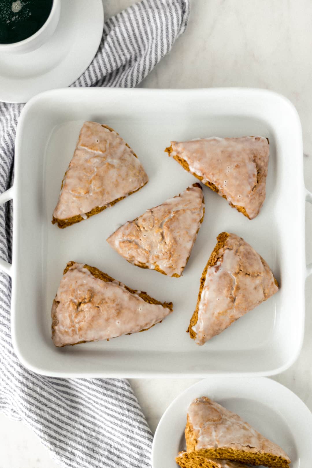 five pumpkin scones on a white dish next to a napkin