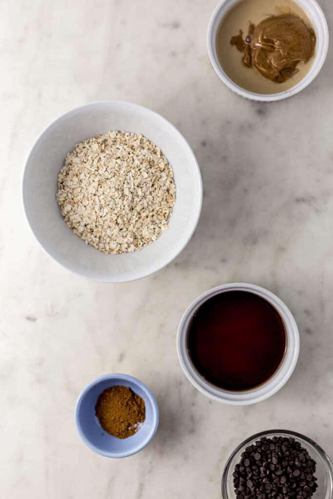 ingredients to make tahini cookies in small bowls on marble surface. 