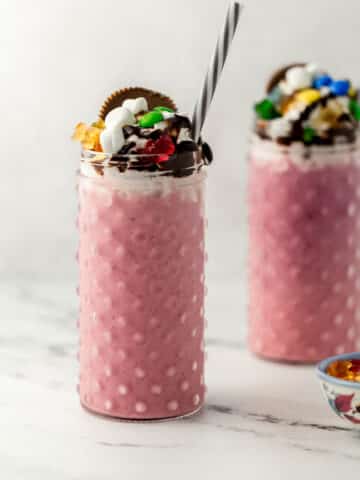 two shakes in glasses next to small blue bowl of candy