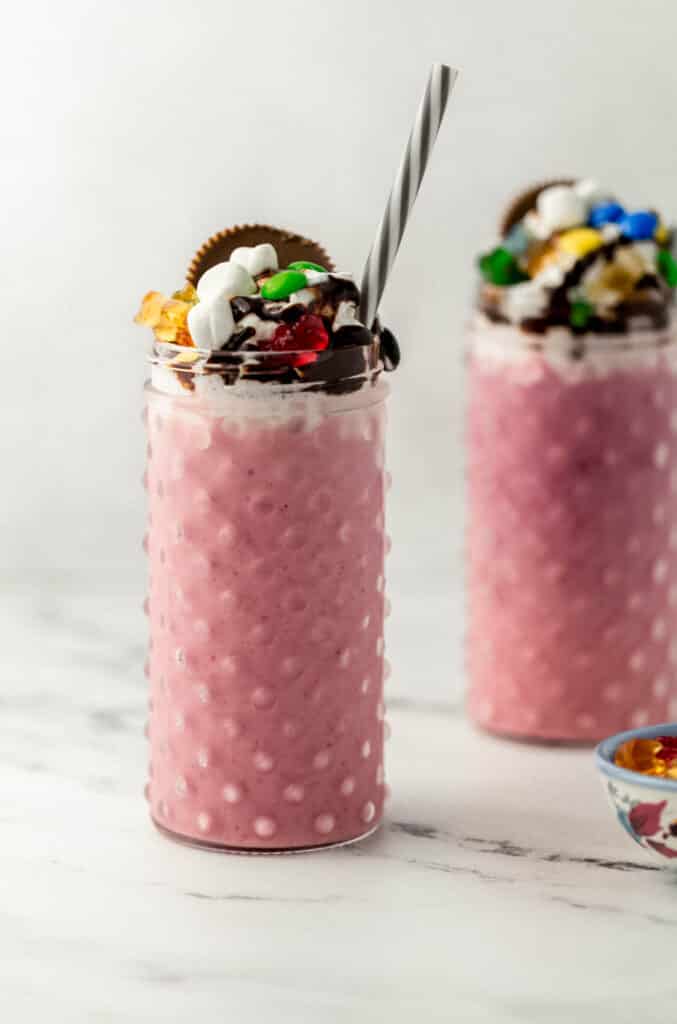 two shakes in glasses next to small blue bowl of candy