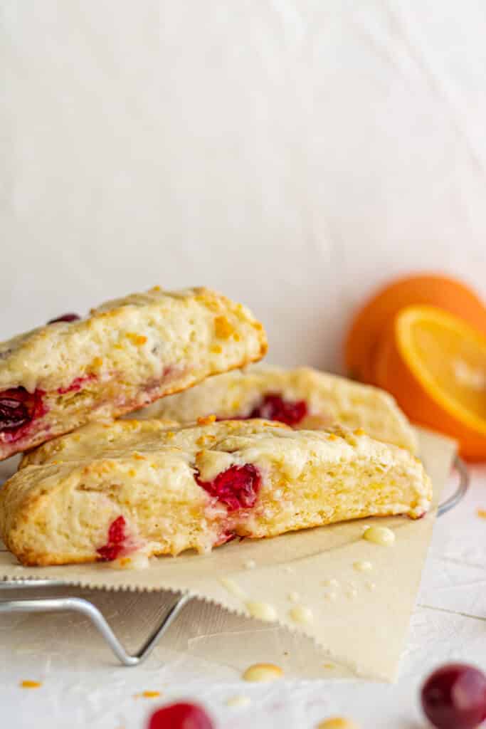 close up side view scones on parchment next to sliced orange