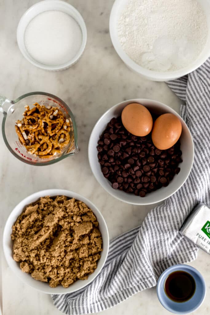 ingredients to make chocolate chip pretzel cookies in separate small bowls and containers. 