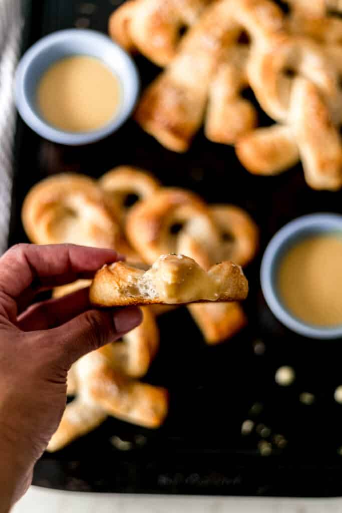 hand holding soft pretzel with mustard sauce on it