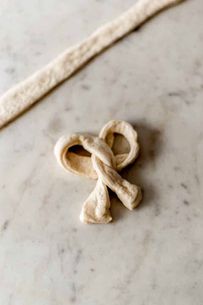 pizza dough made into the shape of a pretzel before baking