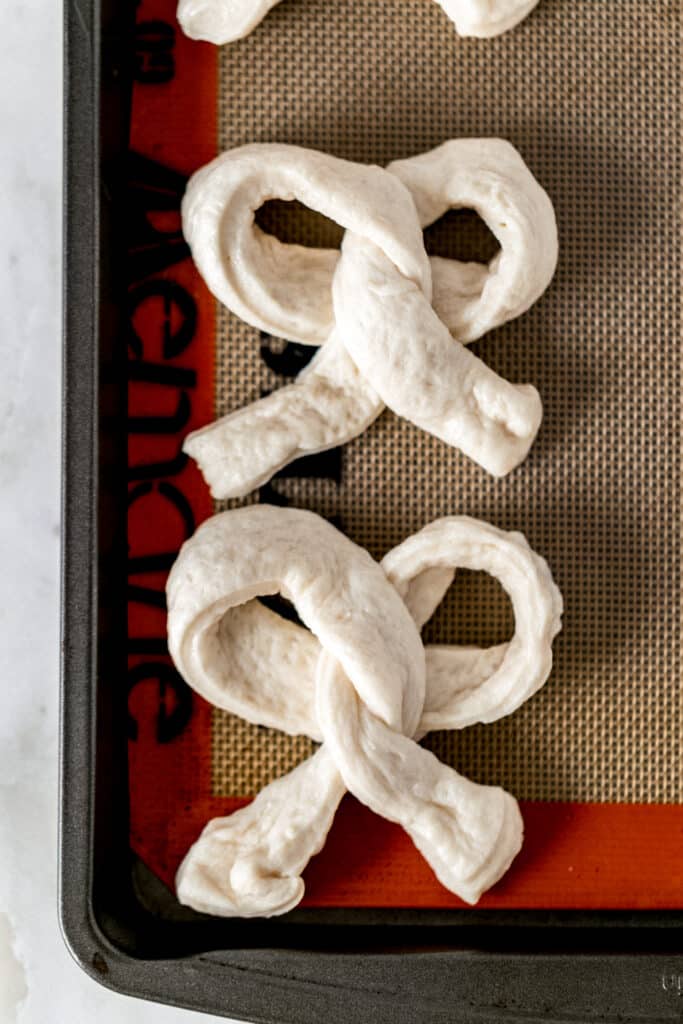 unbaked soft pretzels on sheet pan with silplat