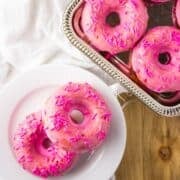 Overhead view of donuts on plate and silver tray.