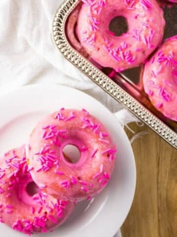 Overhead view of donuts on plate and silver tray.