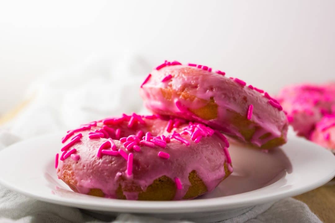 Close up view of two donuts on a white plate. 