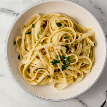 overhead view of bowl of fettuccine pasta topped with parsley beside a fork