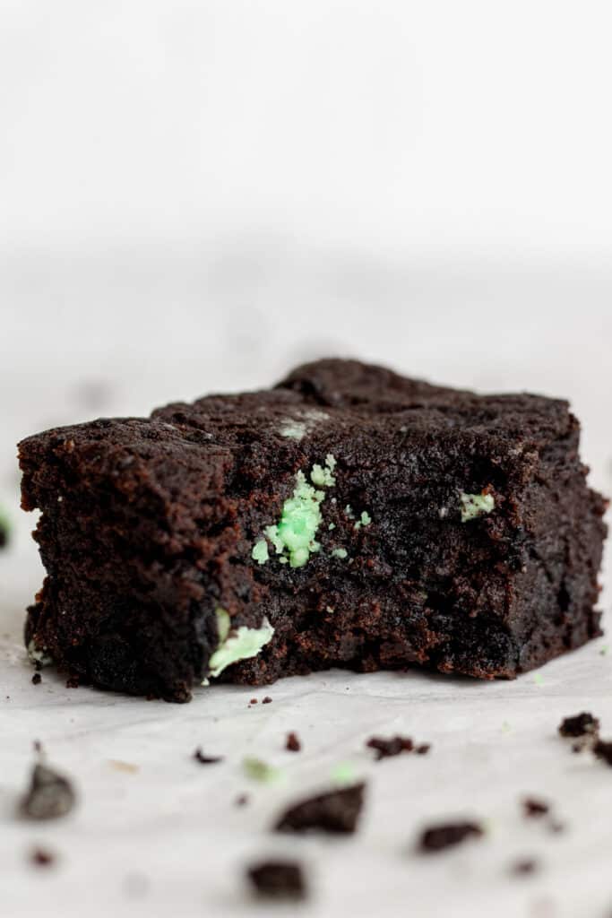 side view of single square cut brownie with a bite into it.