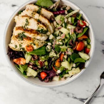 overhead view of finished salad beside a fork on marble surface