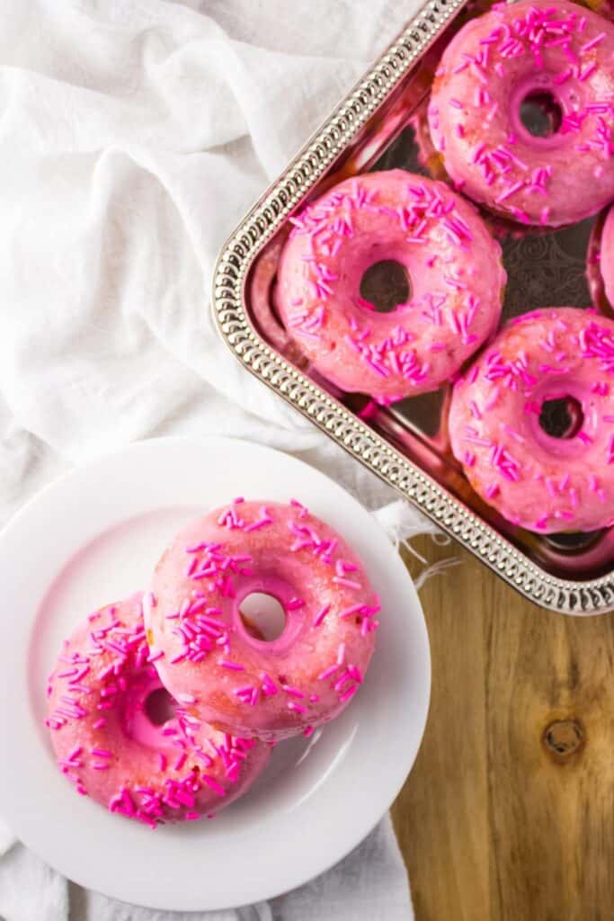 overhead view of doughnuts on silver platter and white plate 