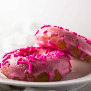 close up side view of two doughnuts on white plate