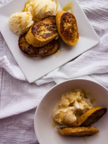 french toast in a white plate and bowl on linen napkin