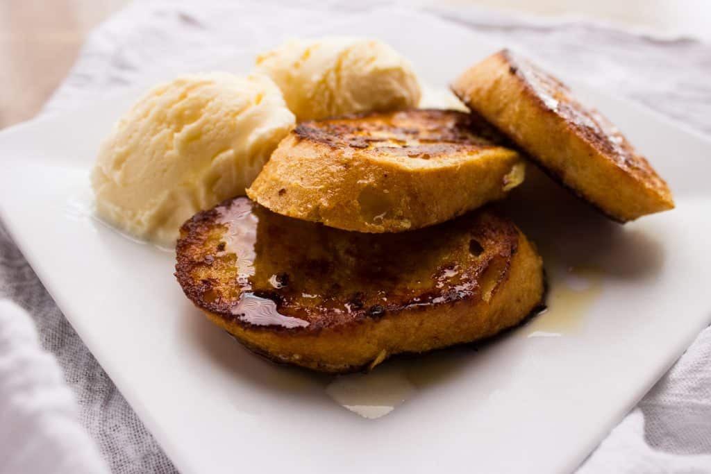 close up side view of french toast and ice cream on white plate 