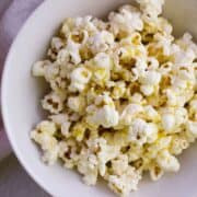 Close up view of white bowl with popcorn in it.