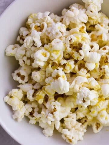 Close up view of white bowl with popcorn in it.