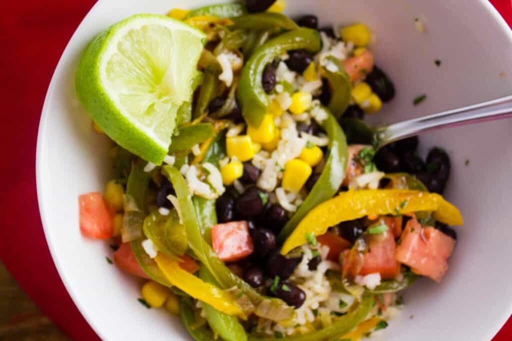 Instead of heading to Chipotle, make this burrito bowl at home instead. Loaded with Cilantro Lime Rice, sauteed bell peppers, chopped tomatoes, and anything else you want. simplylakita.com #chipotle #burritobowl #vegan