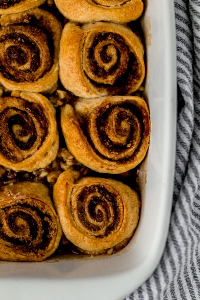 baked sticky buns in white baking dish next to striped cloth napkin