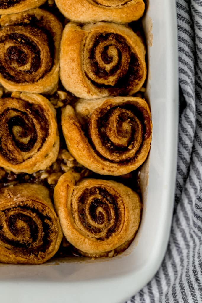 baked sticky buns in white baking dish next to striped cloth napkin