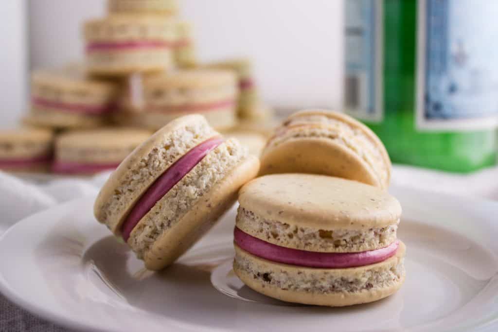 side view blackberry macarons on a plate with some in the background