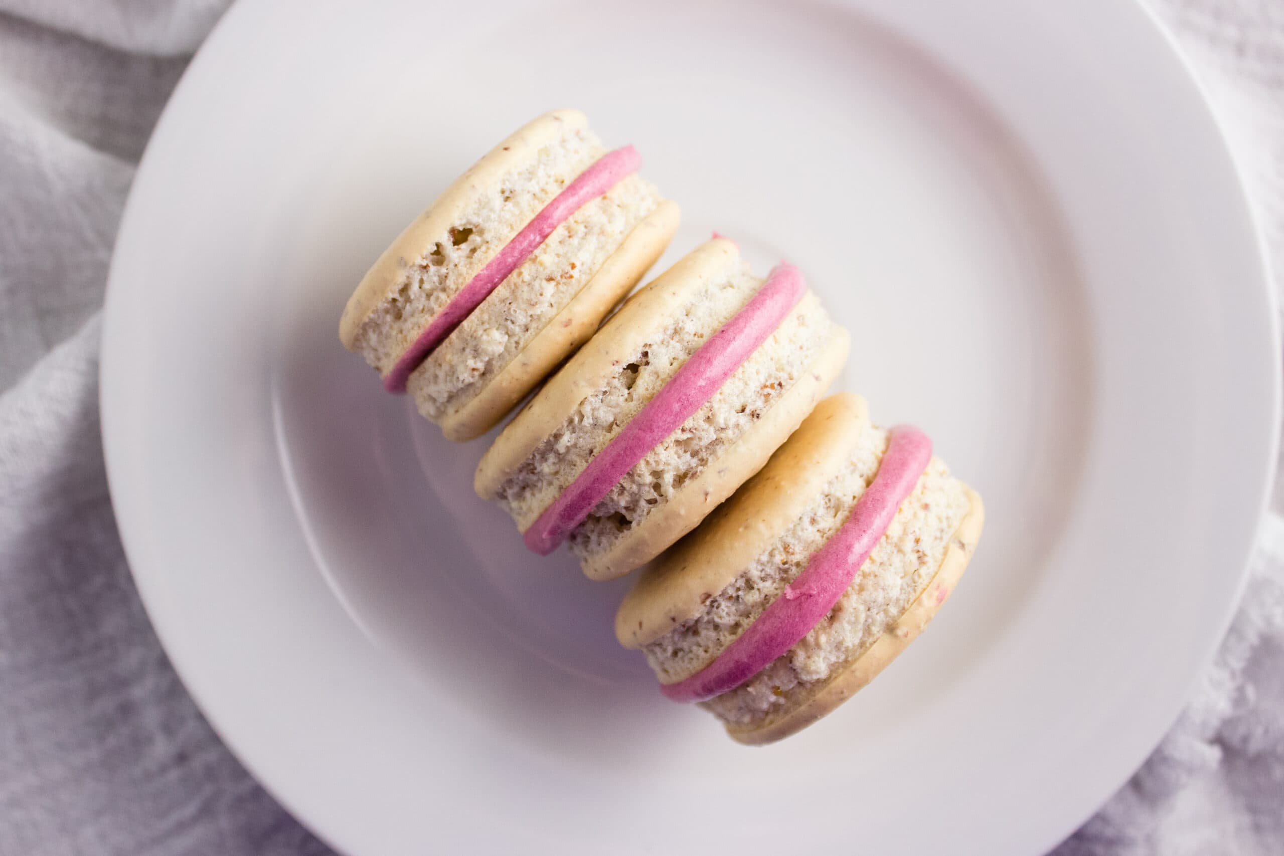 Overhead view of three macarons on a white plate. 